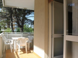appartamento con balcone e un ombrellone con due lettini in spiaggia  